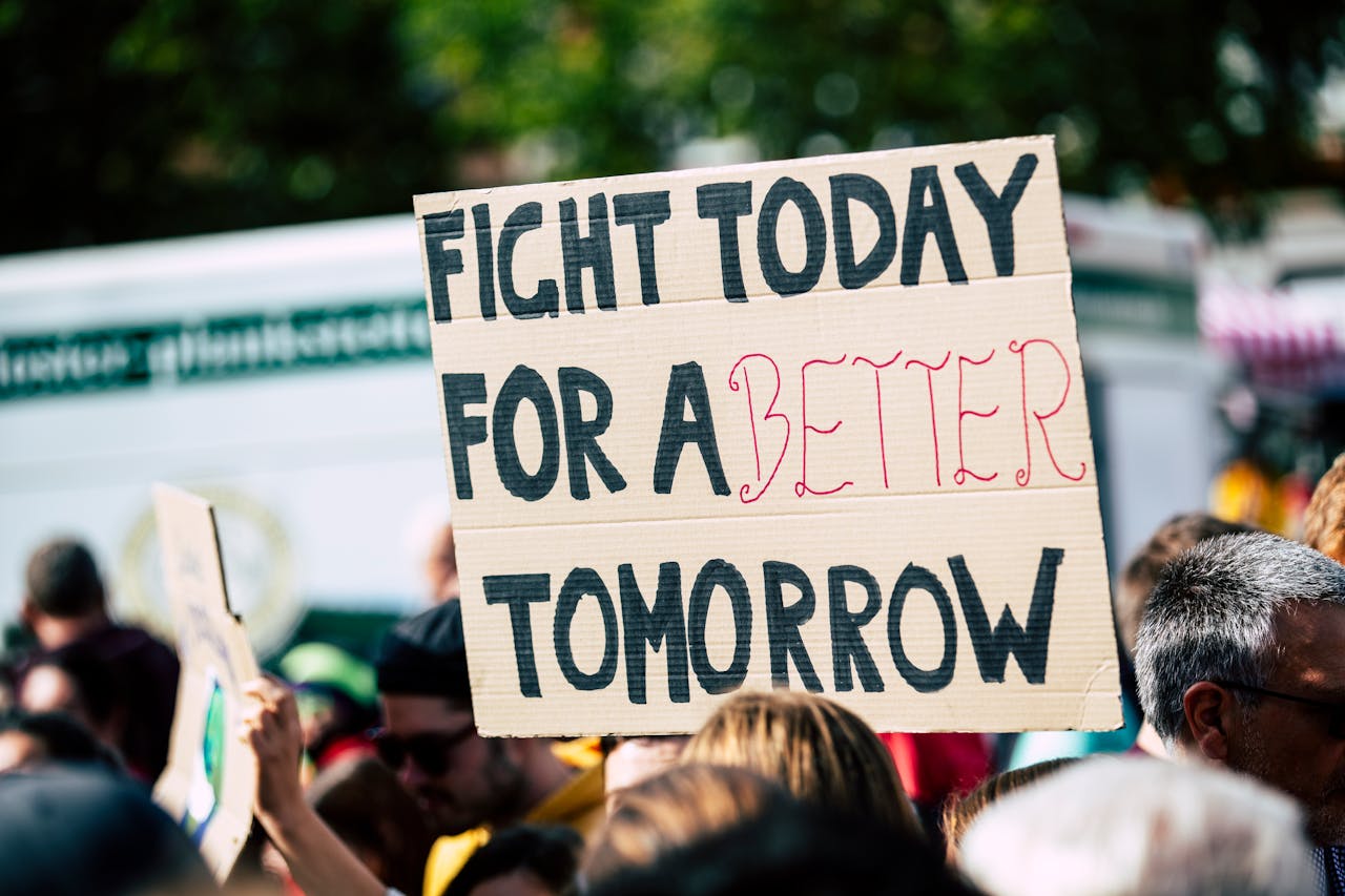 impact-img Crowd holding a protest sign with Fight Today for a Better Tomorrow, outdoors and during the day.