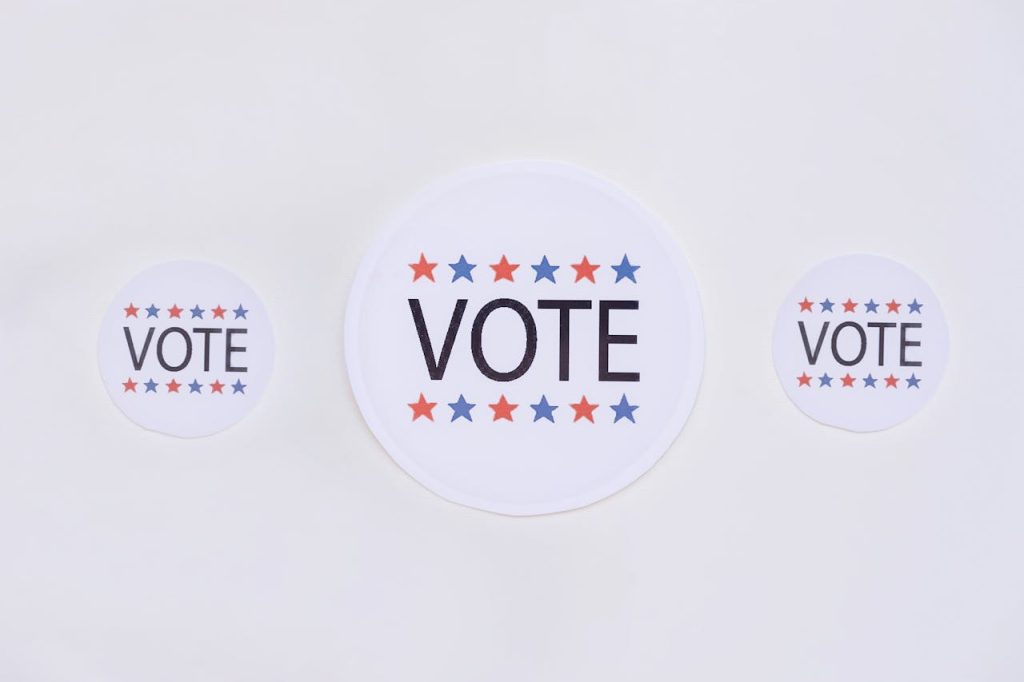 vote-badges-on-white-surface-8846784 Three vote stickers featuring stars symbolize political participation on a white surface.