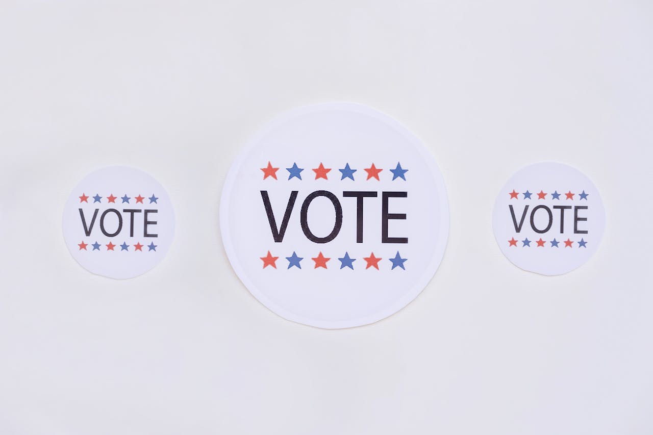 Three vote stickers featuring stars symbolize political participation on a white surface.